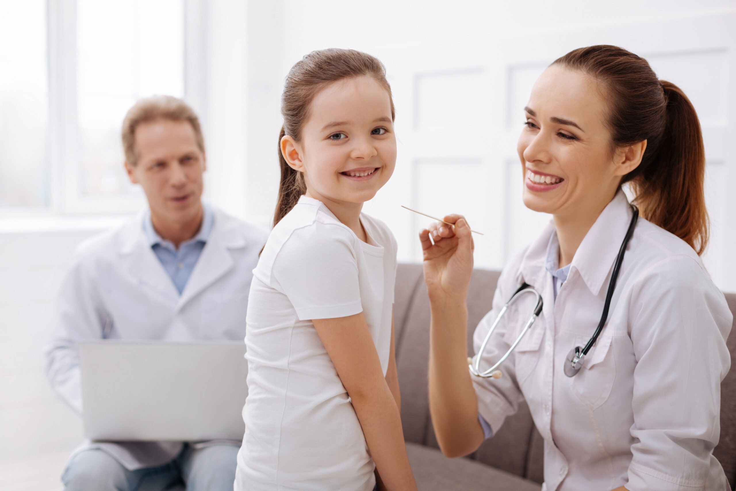 Regular visit. Pretty smiling cute child being completely unafraid of the doctors and enjoying their company while they running a few easy tests